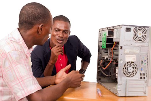 young technician learning repairs a computer sitting in front of an instructor