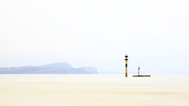 The view past a marker post across Lake Garda from the resort town of Sirmione.  Sirmione is at the southern end of the lake which is in North East Italy.