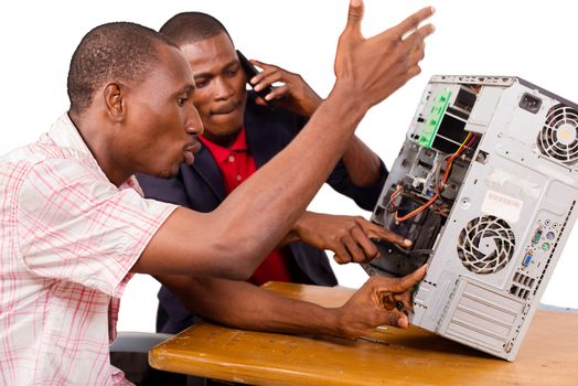 Young technicians sitting and working on broken computer at office