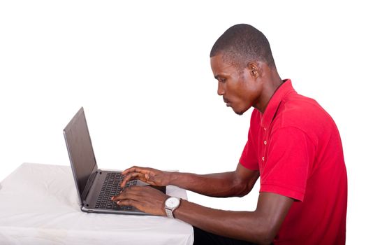 Young businessman working on his laptop in the office. Young african executive sitting at his desk, surfing the internet on laptop..