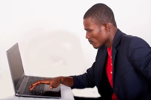 Young businessman working on his laptop in the office. Young african executive sitting at his desk, surfing the internet on laptop.