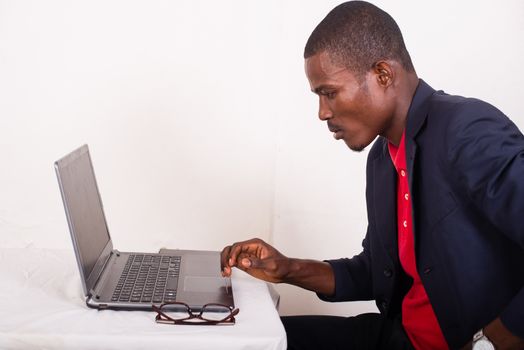 young man in a business suit working at a desk on a laptop