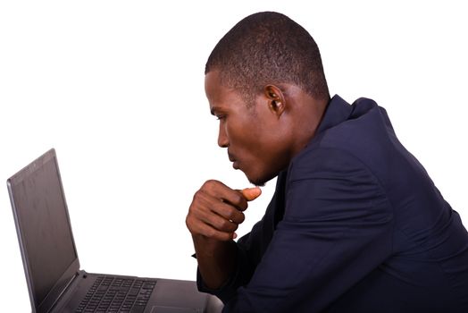 young man in a business suit working at a desk on a laptop