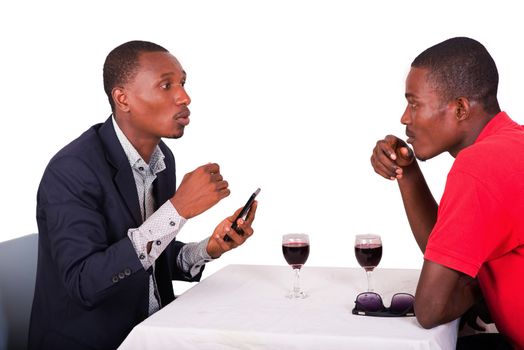 two businessmen sitting at the restaurant talking business while drinking wine.