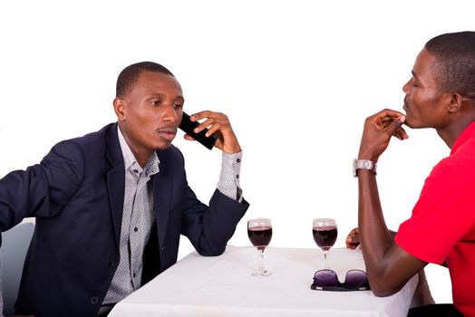 businessman sitting at restaurant with his colleague talking on the phone and drinking wine