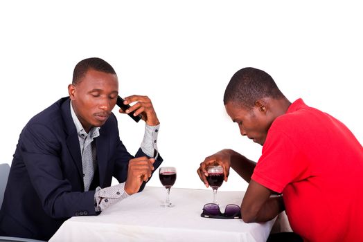 businessman sitting at restaurant with his colleague talking on the phone and drinking wine