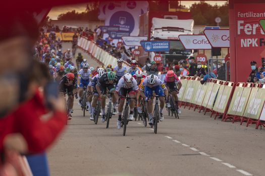 Cyclists from different teams, pedaling hard in the final sprint, in the area of the finish line of the fourth stage of La Vuelta a España 2020.