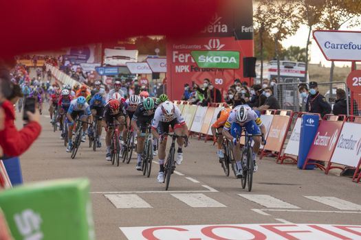 Cyclists from different teams, pedaling hard in the final sprint, in the area of the finish line of the fourth stage of La Vuelta a España 2020.
