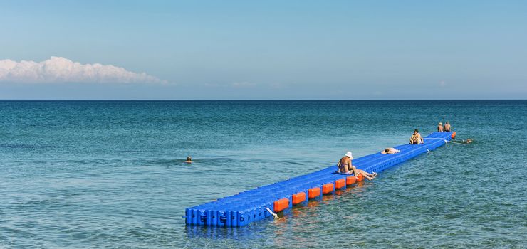 Zakynthos, Laganos - June 07, 2016: The pontoon jetty is installed in the sea. On the pontoon berth sunbathing vacationers