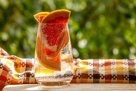 A glass of water with grapefruit in the garden background