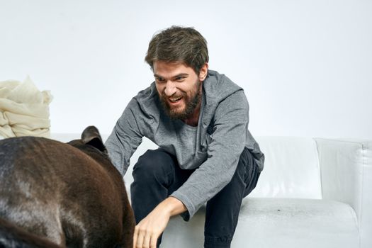 Happy man and dog on the couch In a bright room pet is a friend of man. High quality photo