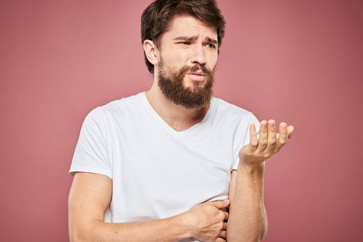 emotional man white t shirt sad facial expression pink background. High quality photo