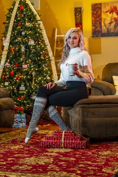 A gorgeous blonde model enjoys the holiday season at home with a Christmas tree and presents