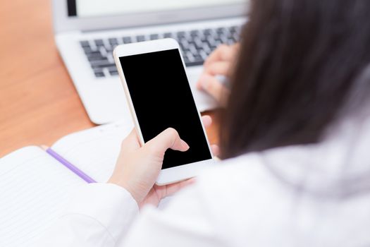 Asian woman hand holding a white phone with screen above on desk, girl using mobile with laptop, communication online digital concept.