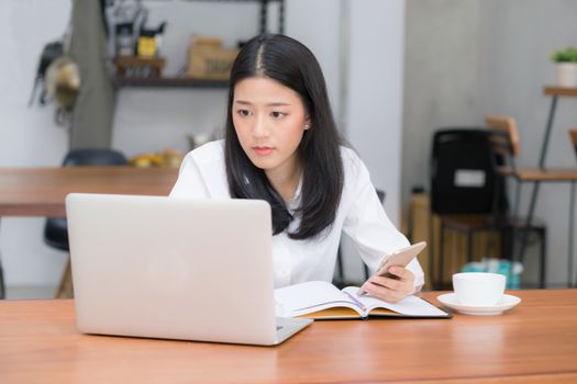 Beautiful asian young businesswoman excited and glad of success with laptop, girl taking mobile phone and working coffee shop on cement background, career freelance business concept.