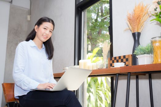 Beautiful asian young woman working online on laptop sitting at coffee shop, professional female freelancer using notebook computer with connect to internet for distance job.