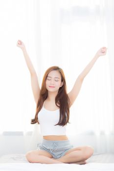 Beautiful young asian woman stretch and relax in bed after wake up morning at bedroom, new day and resting for wellness, lifestyle concept.