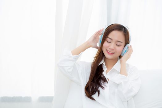 Beautiful asian young woman enjoy listen music with headphone while sitting in bedroom, relax girl with earphone internet online, leisure and technology concept.