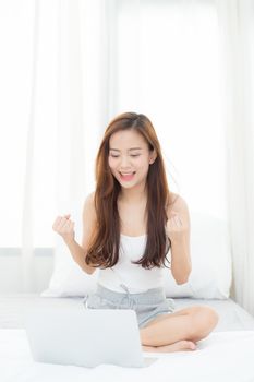 Beautiful happiness young asian woman using laptop work with success on bed in the home, girl and notebook shopping online with glad, communication concept.