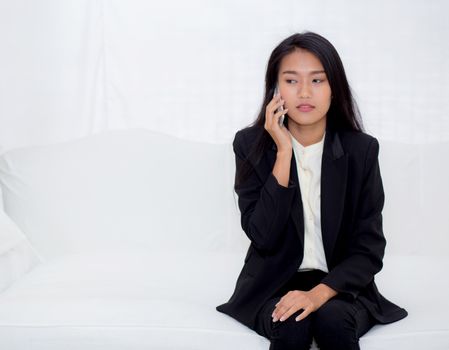 Beautiful young asian woman talking phone and smile in the living room, businesswoman sitting on sofa,businesswoman calling telephone, communication concept.