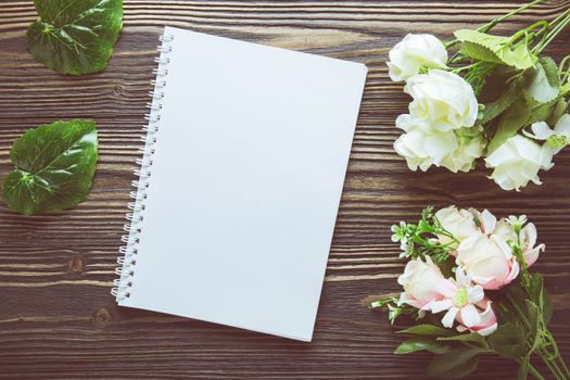 Bouquet of flower and empty diary notebook on rustic wooden table with copy space, mockup template with flower and note, top view, vintage retro style.
