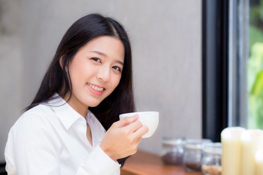Beautiful  young asian woman drinking coffee and smile in the morning at cafe, girl sitting in coffee shop for breakfast and leisure during free time.