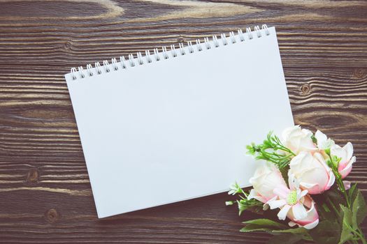 Bouquet of flower and empty diary notebook on rustic wooden table with copy space, mockup template with flower and note, top view, vintage retro style.