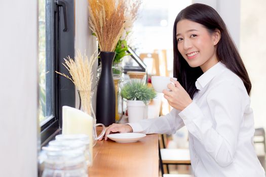 Beautiful  young asian woman drinking coffee and smile in the morning at cafe, girl sitting in coffee shop for breakfast and leisure during free time.
