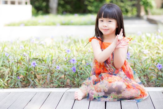 Beautiful portrait little girl asian of a smiling standing on green grass at the park, kid leisure and joyful in outdoor.