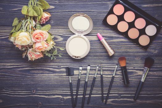 Top view a collection of cosmetic makeup and flower on wooden table background, products cosmetic fashion concept, vintage retro style.