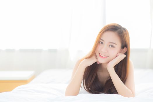 Beautiful portrait young asian woman lying and smile while wake up with sunrise at morning, lifestyle and relax concept.