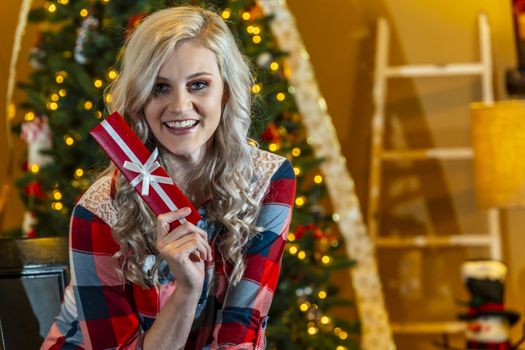 A gorgeous blonde model enjoys the holiday season at home with a Christmas tree and presents