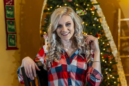 A gorgeous blonde model enjoys the holiday season at home with a Christmas tree and presents