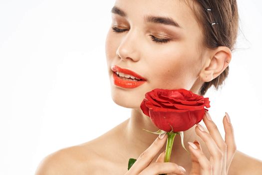 charming brunette girl with makeup on her face and a red rose in her hand. High quality photo