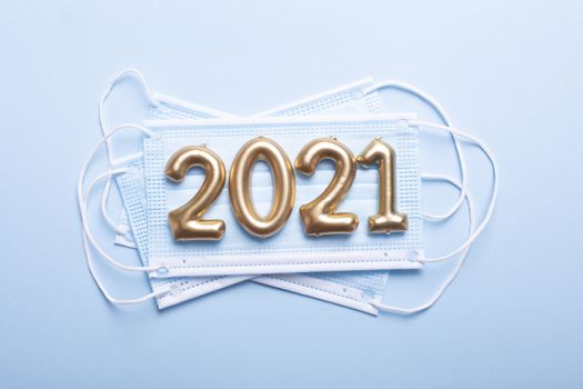 Gold numbers 2021 with face mask on blue background. Happy new pandemic year
