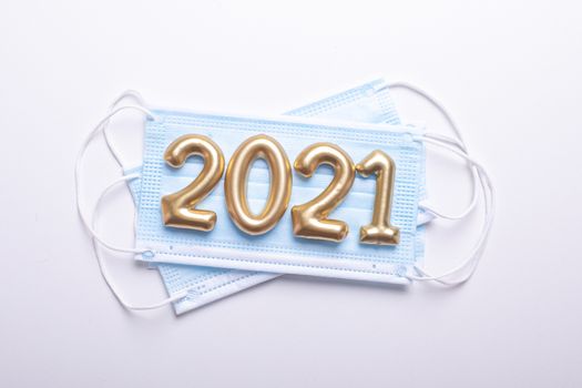 Gold numbers 2021 with face mask on white background. Happy new pandemic year