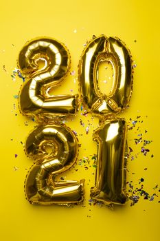 2021 concept new year from golden foil balloon and confetti on yellow stock photo