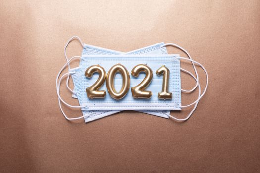 Gold numbers 2021 with face mask on copper background. New pandemic year