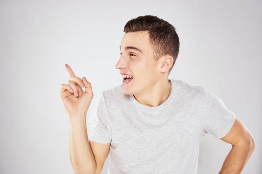 Man in a white t-shirt emotions gestures with hands close-up cropped view light background. High quality photo