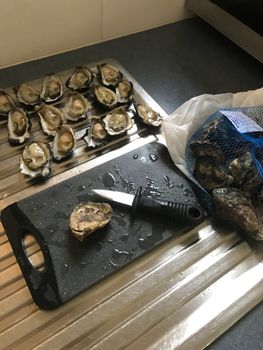 Freshly opened oysters with an oyster knife and chopping board