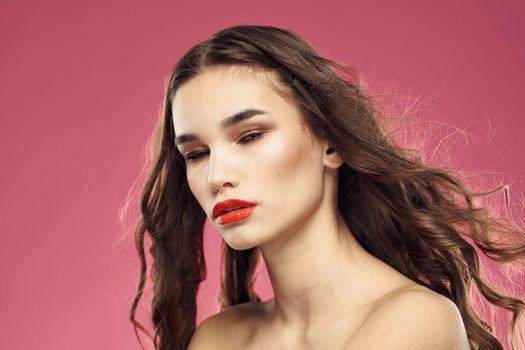 Beautiful woman with red lips on a pink background nude shoulders cropped view. High quality photo