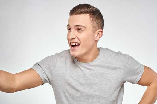 man in gray t-shirt emotions light background cropped view. High quality photo