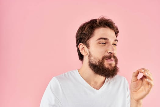 Man in white t-shirt gestures with hands emotions lifestyle cropped view pink background. High quality photo