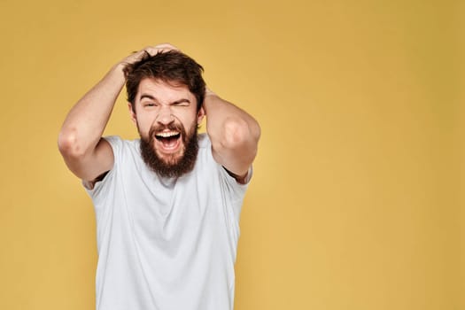 Bearded man white t-shirt emotions gestures with hands fun yellow background. High quality photo