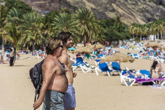 Spain, Tenerife - September 12, 2016 Two men go to the beach to swim and sunbathe