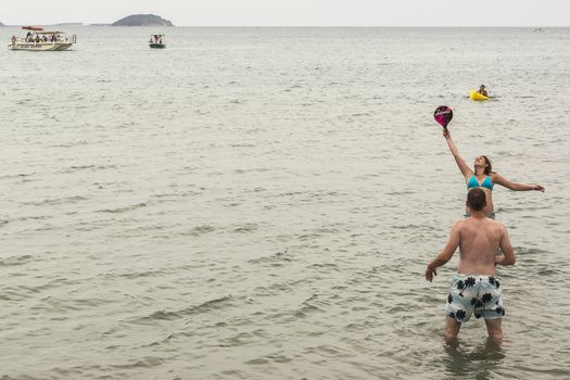 Greece, Zakynthos Island - June 19, 2016: Young woman and young man playing games standing in water