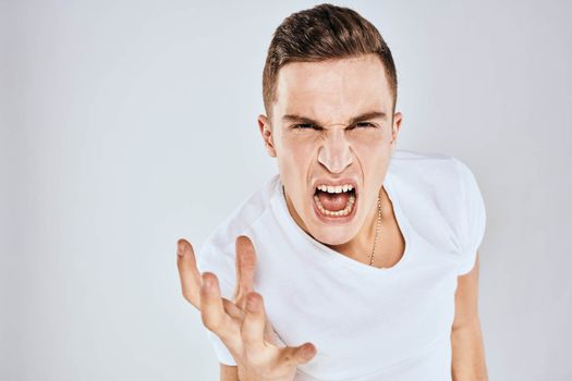 emotional man gesturing with his hands displeased facial expression white t-shirt cropped. High quality photo