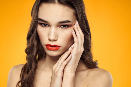 beautiful brunette red lips bare shoulders skin care yellow background. High quality photo