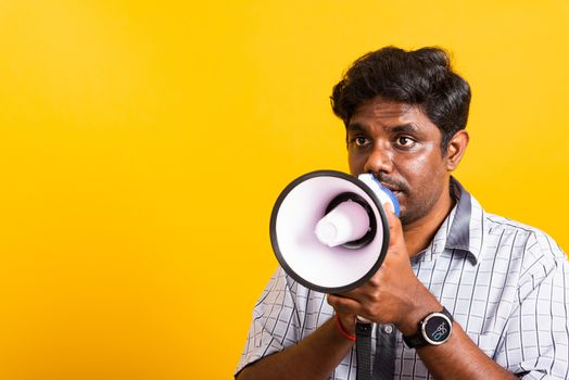 Asian happy portrait young black woman standing to make announcement message shouting screaming in megaphone, studio shot isolated on yellow background with copy space