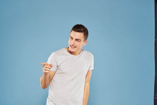 cheerful man in a white t-shirt gesturing with his hands emotions blue background. High quality photo